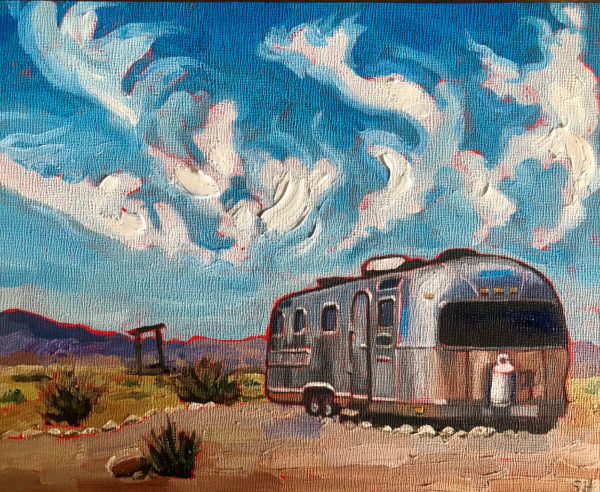 Airstream trailer in desert under clouds